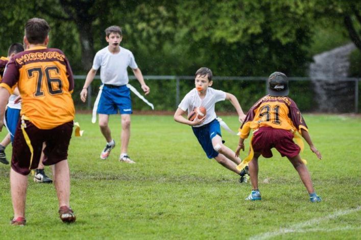 Children playing flag football. A boy runs with the ball fully concentrated.